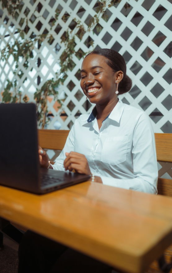 Young woman smiling while working on a laptop.